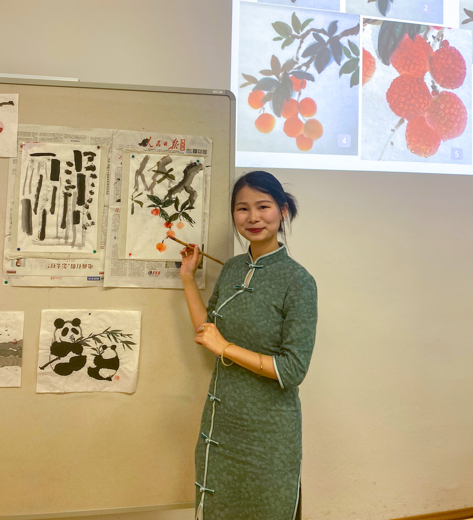 Kursleiterin des Malkurs zeigt an der Tafel die Maltechniken der chinesischen Malerei vor 