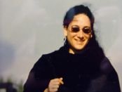 Andrea Strutz Portraitfoto, Sonnenbrille, dunkle Haare, schwarzer Pullover, grauer Himmel im Hintergrund