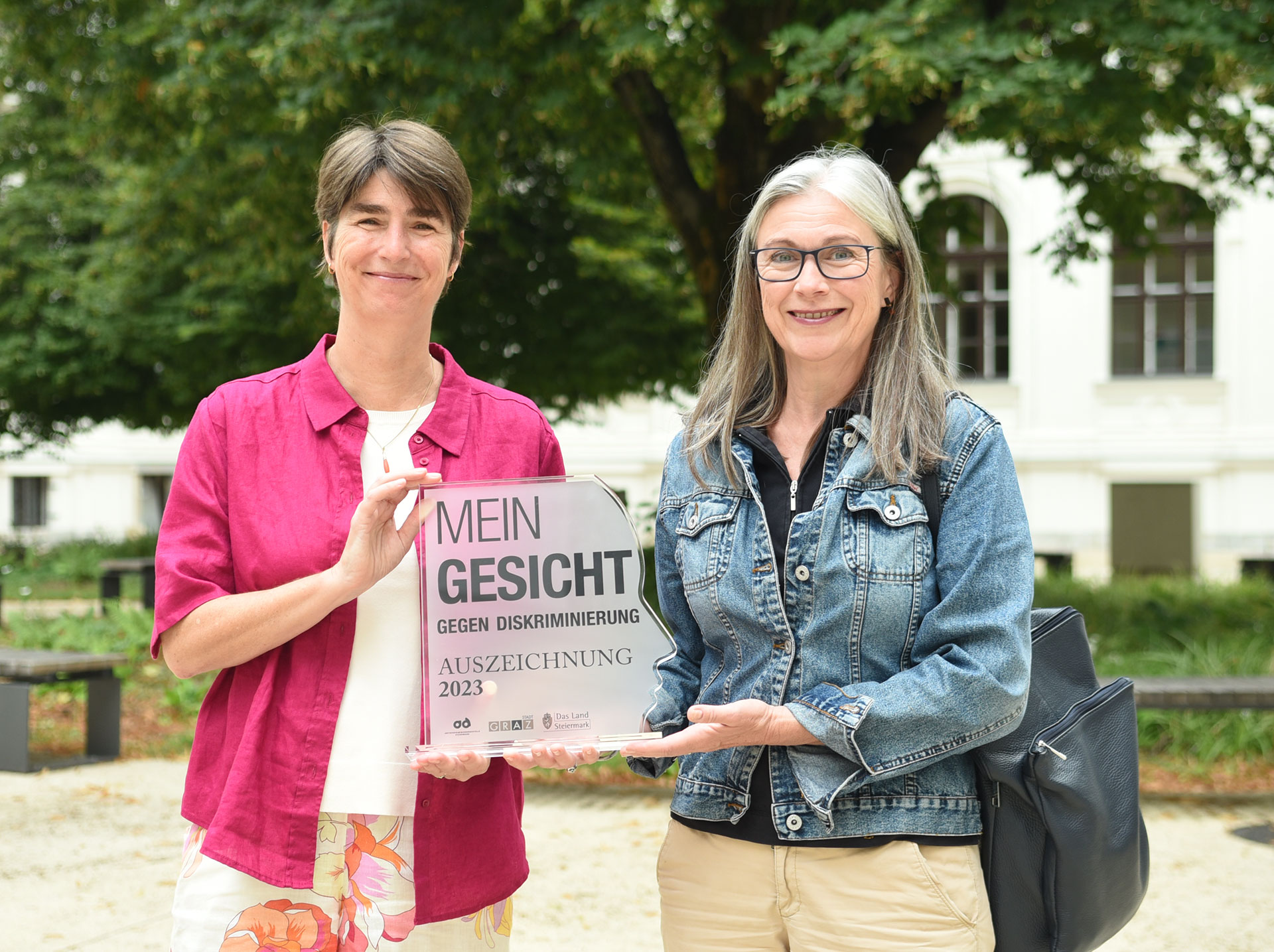 Mireille van Poppel und Barbara Hey mit der Auszeichnung der Antidiskriminierungsstelle Steiermark im Innenhof der Uni Graz ©Uni Graz/Eklaude