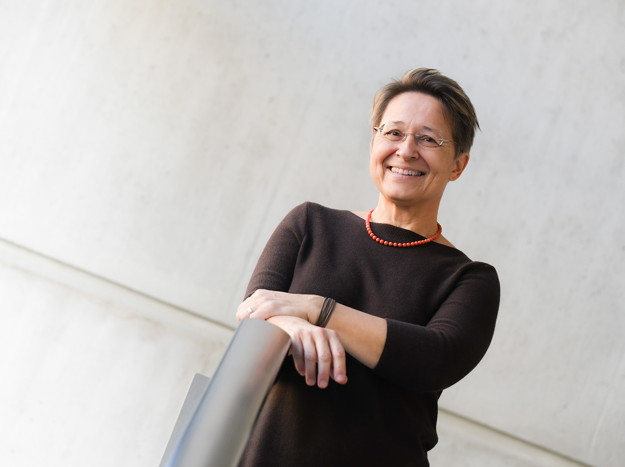 Anita Ziegerhofer, Portrait, vor grauer Betonwand, die Hände auf einem Edelstahl-Geländer ©Uni Graz/Tzivanopoulos