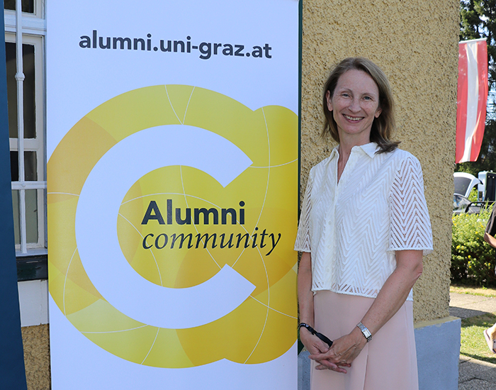 Frau steht nehmen Roll-up mit Alumni-Sujet ©Uni Graz/Martina Mayer-Krauss