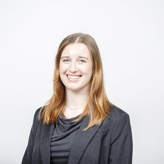 ein Portraitfoto einer Person mit brünetten Haaren und schwarzer Kleidung