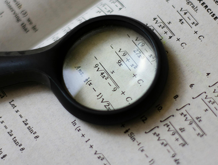 Eine Lupe und mathematische Rechnungen und Formeln ©Pexels