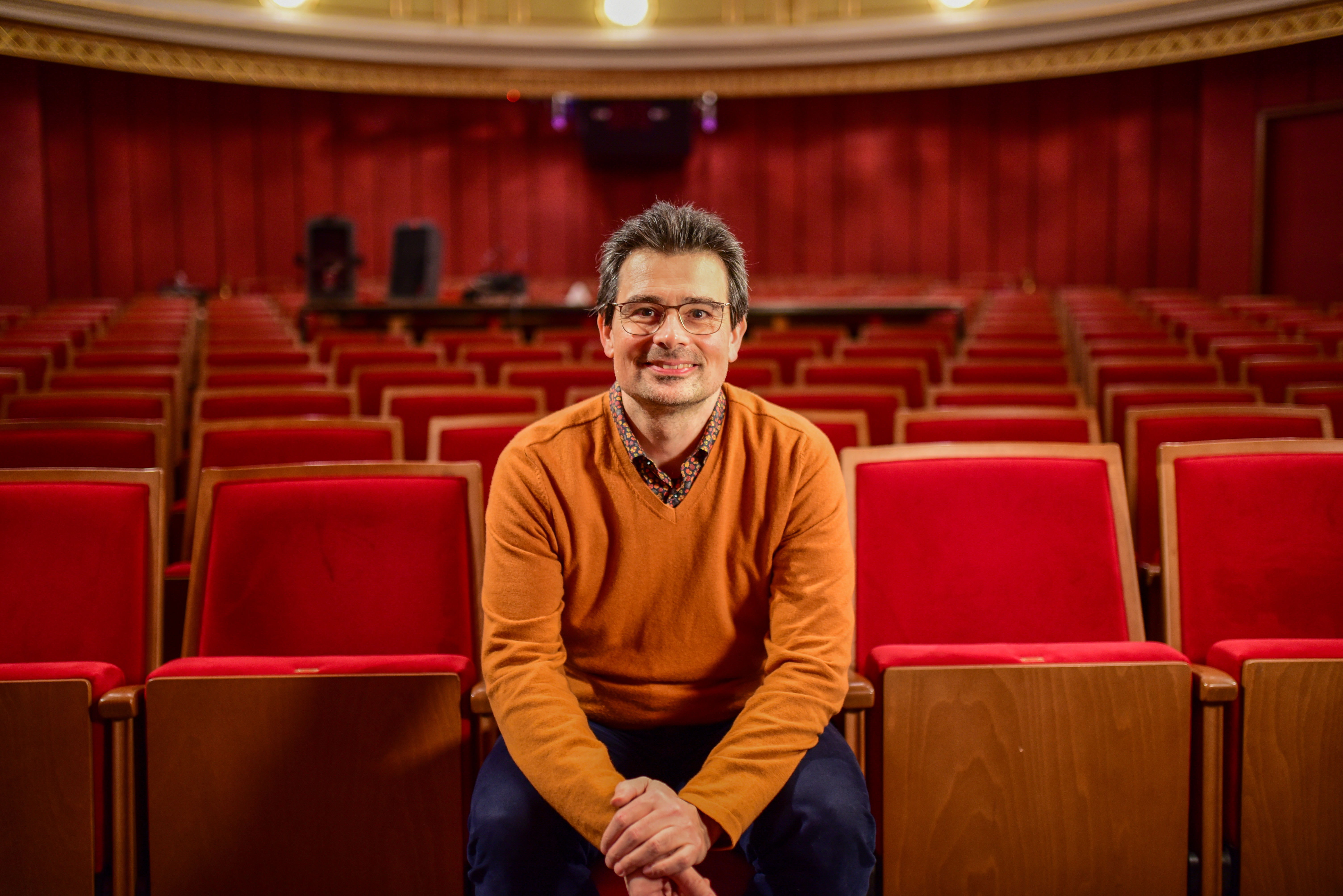 Ein Mann sitzt auf den roten Sesseln im Saal des Grazer Schauspielhauses ©Uni Graz/Tzivanopoulos