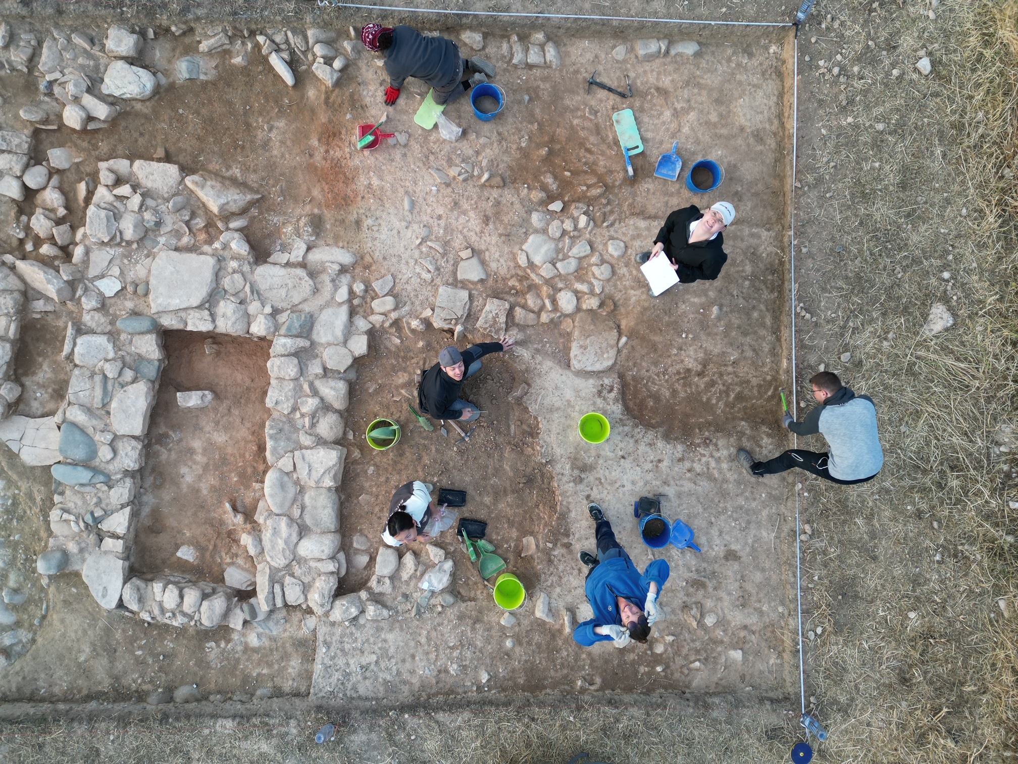 Aufnahme Grabungsstätte von oben; Ausgrabungsteam blickt nach oben; Grundriss eines Gebäudes ist erkennbar ©Erimi Pitharka Archaeological Project