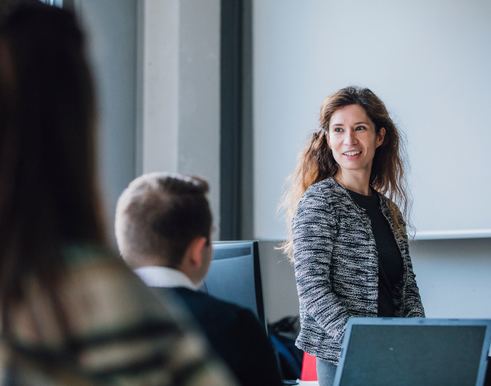 Teacher in the seminar room, looking at students and smiling. ©Uni Graz/Kanizaj