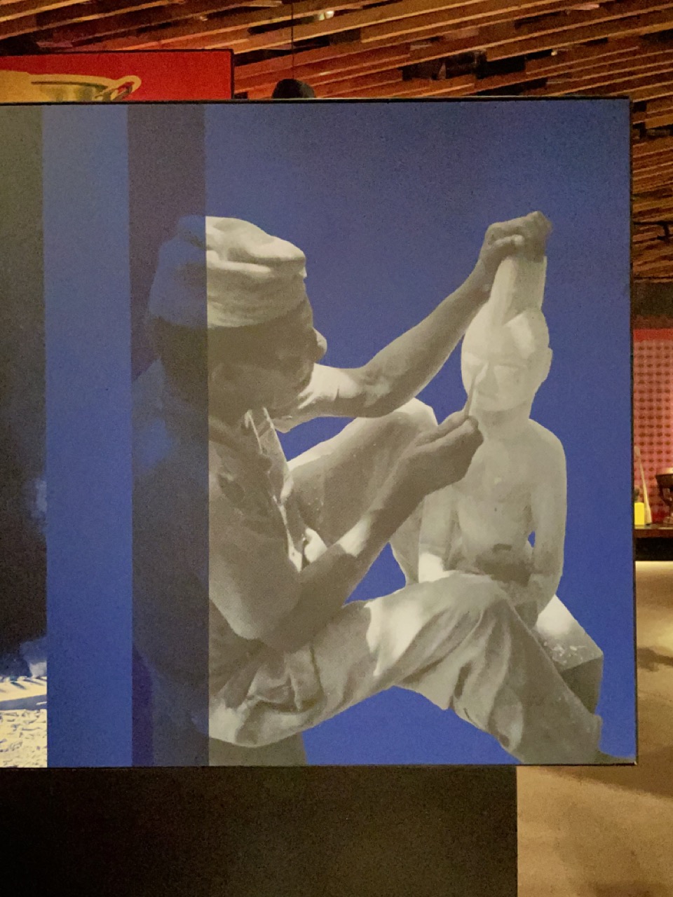 Wood Carving ©J. Randle Centre Lagos/K. Oke The first image depicts a museum banner on which, against a blue background, a person is shown carving a wooden statute. {f:if(condition: 'J. Randle Centre Lagos/K. Oke', then: '©J. Randle Centre Lagos/K. Oke')}