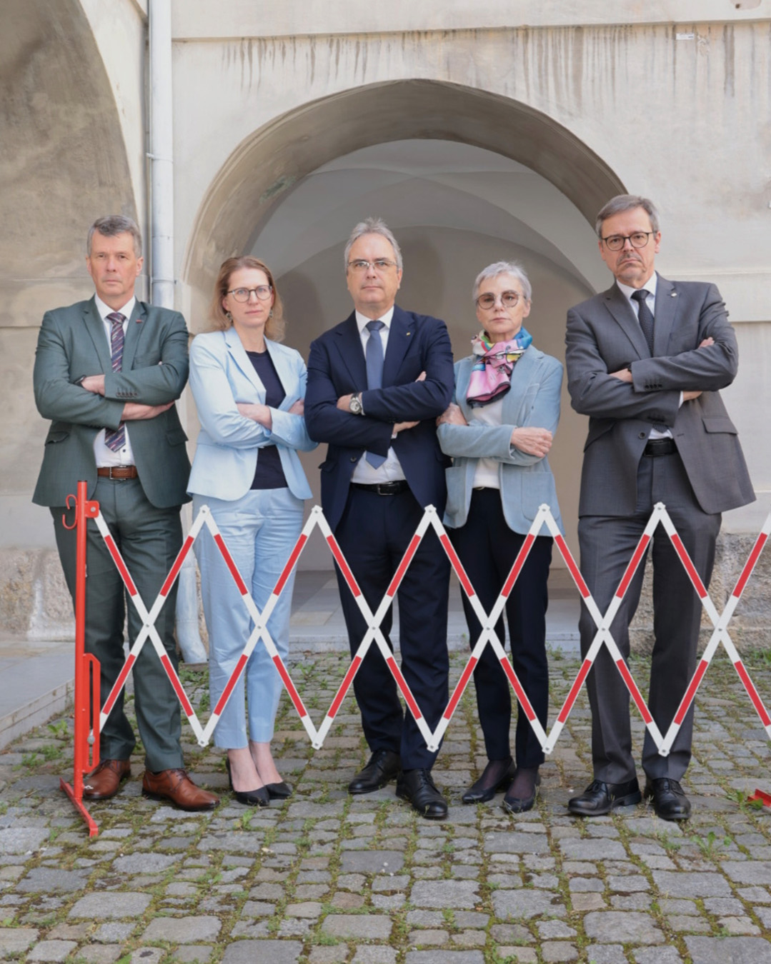 Eine Gruppe von fünf Menschen in geschäftlicher Kleidung steht gemeinsam in einem Torweg, die Arme verschränkt. ©Harry Schiffer Photodesign