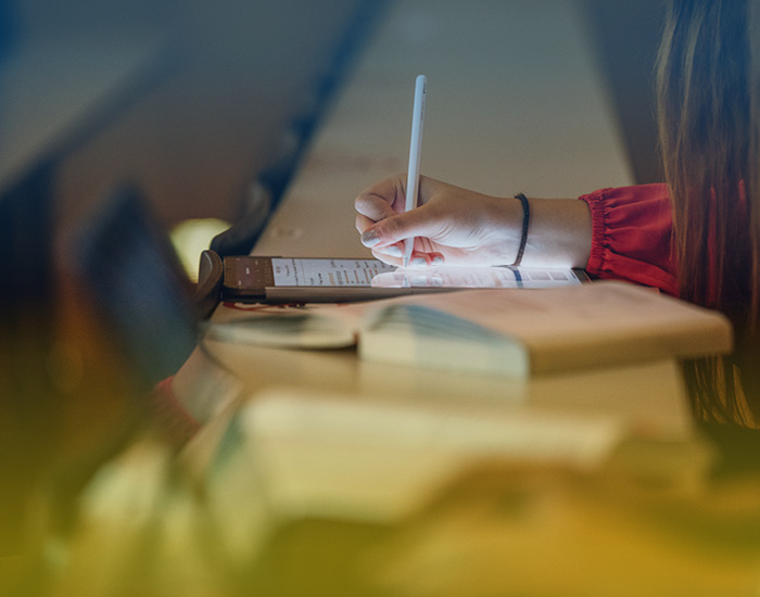 A young lady in a lecture hall, in front of her a tablet, a laptop and books, subject image for Ukraine University of Graz language courses ©Uni Graz/Kanizaj