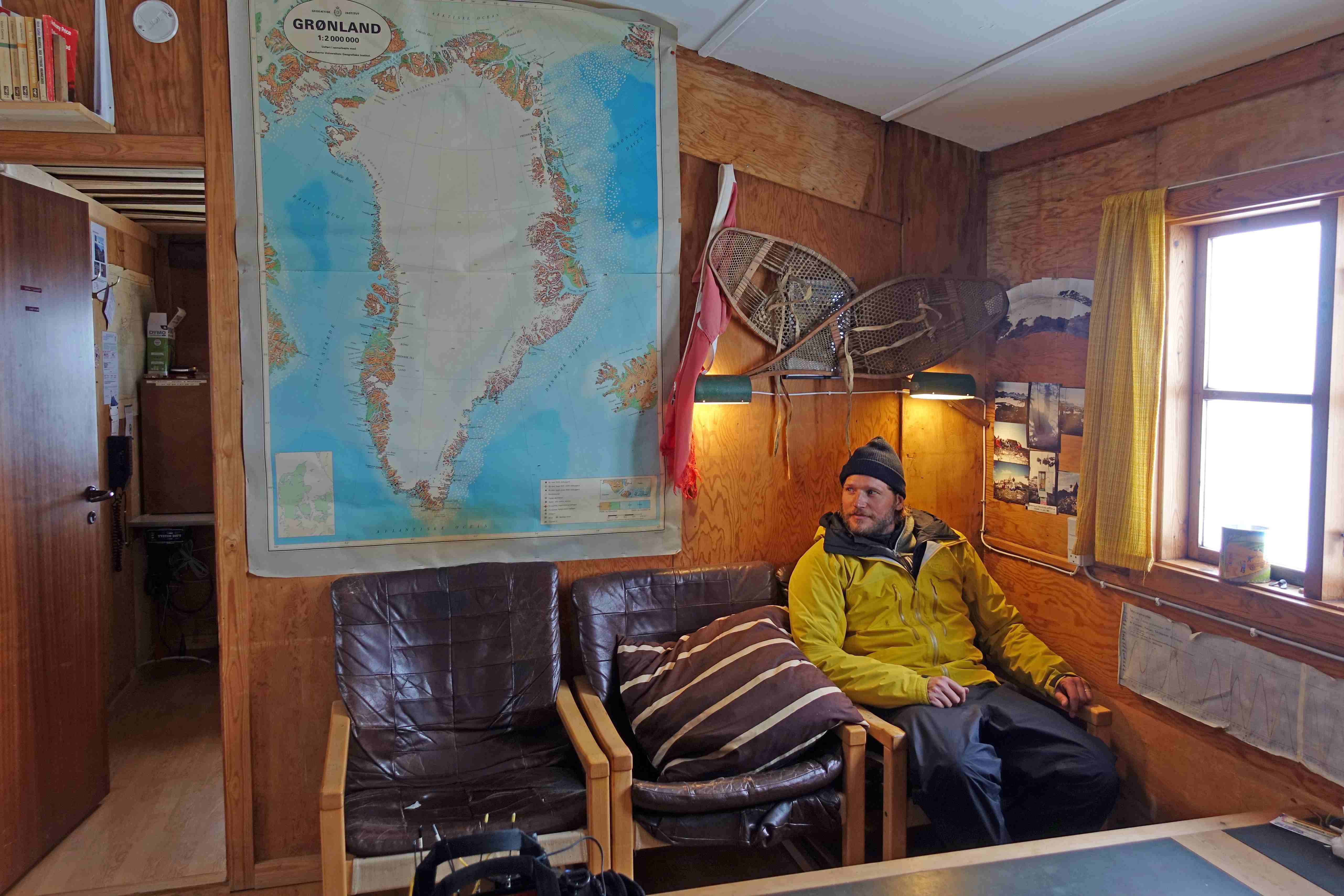 Sebastian Stroebel in einer Hütte mit einer Arktis-Landkarte im Hintergrund