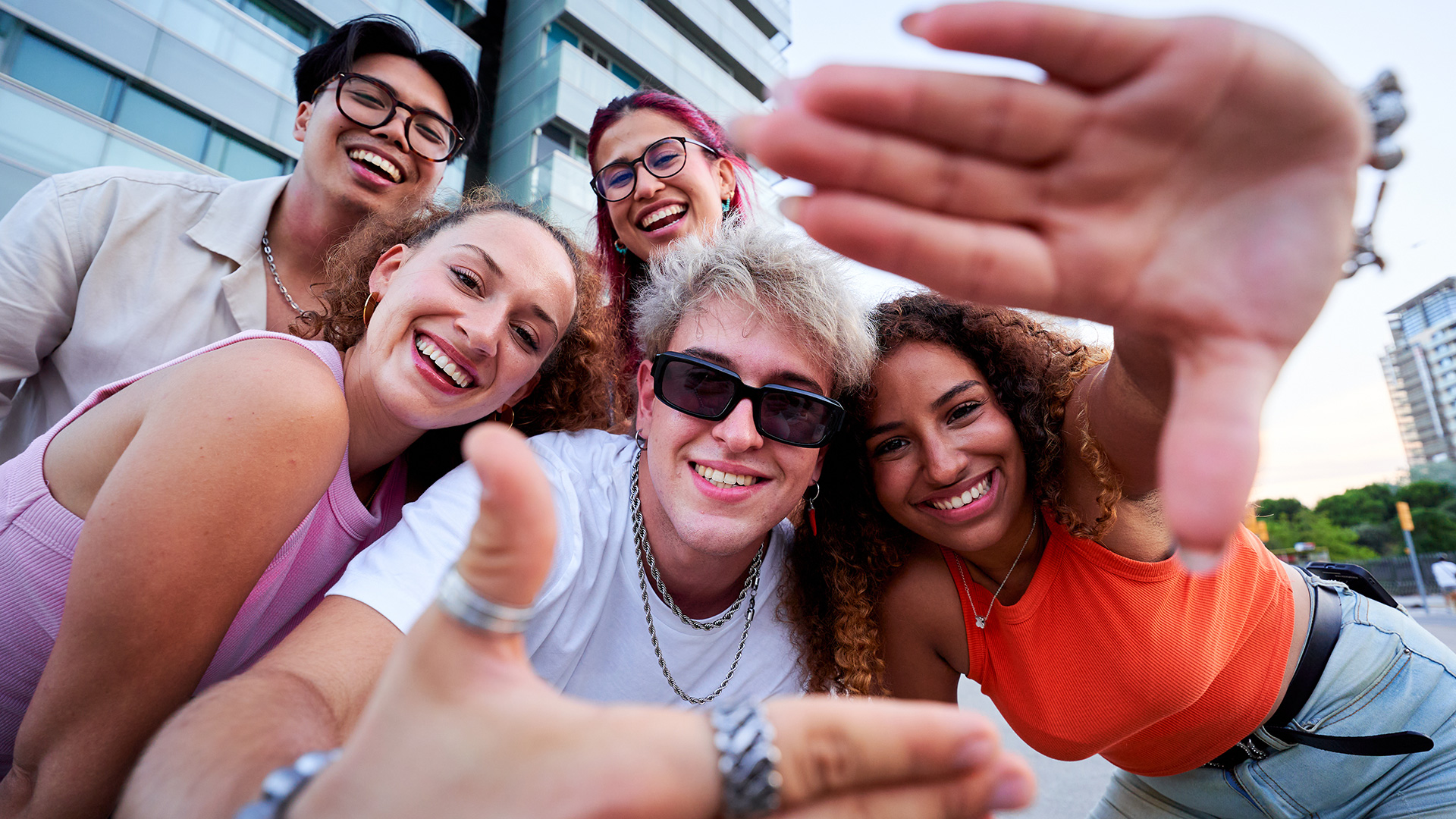 Jugendliche lachen in die Kamera und bilden mit ihren Händen einen Schnappschuss-Rahmen