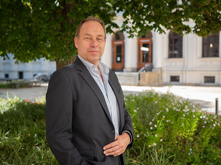 Portrait von Georg Eisenberger im Innenhof der Uni Graz vor einem Baum ©Uni Graz/Radlinger