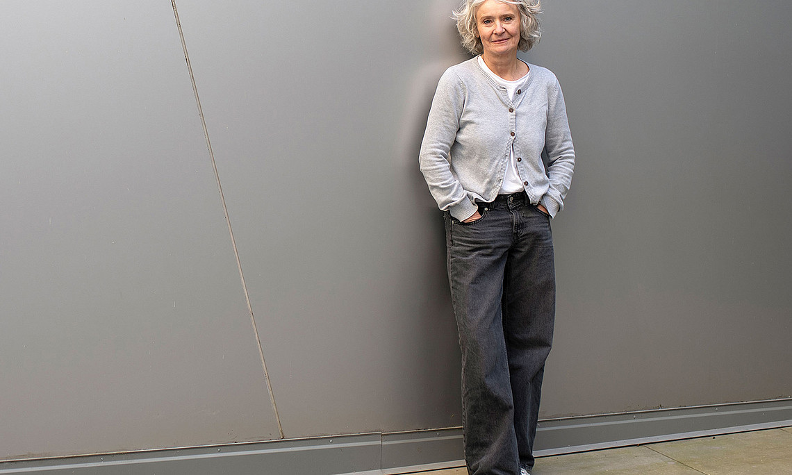 Claudia Traunmüller, leaning against a grey wall