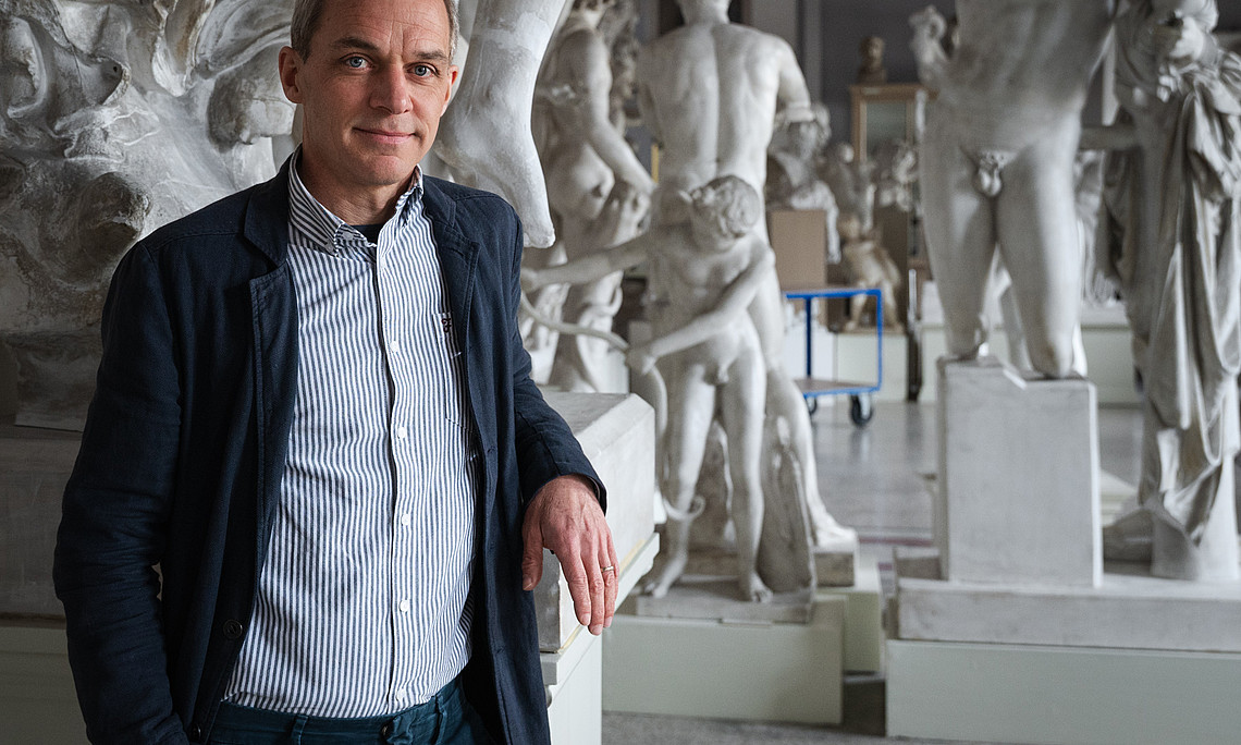 Ein Mann steht vor antiken Statuen 