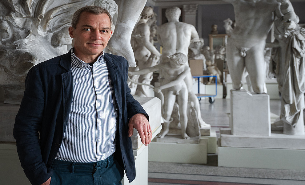 Ein Mann steht vor antiken Statuen 
