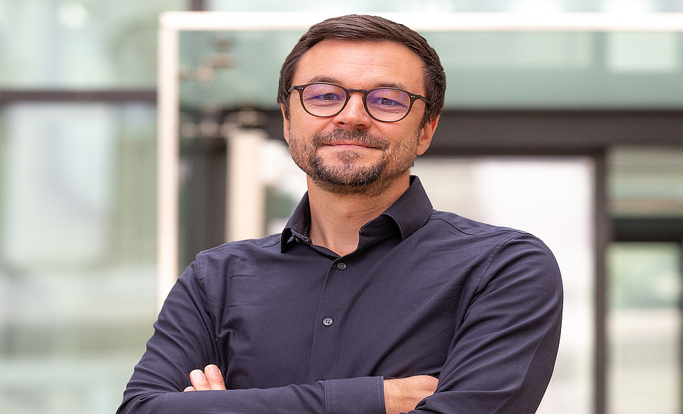 Neurowissenschaftler Stephan Vogel mit verschränkten Armen vor dem Eingang zur Universitätsbibliothek