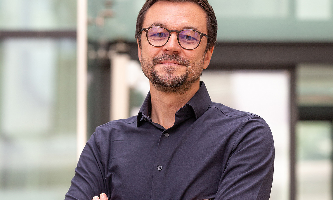 Neuroscientist Stephan Vogel with his arms folded in front of the entrance to the university library