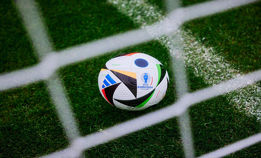 Ein Fußball hinter einem Tornetz auf einem Fußballfeld