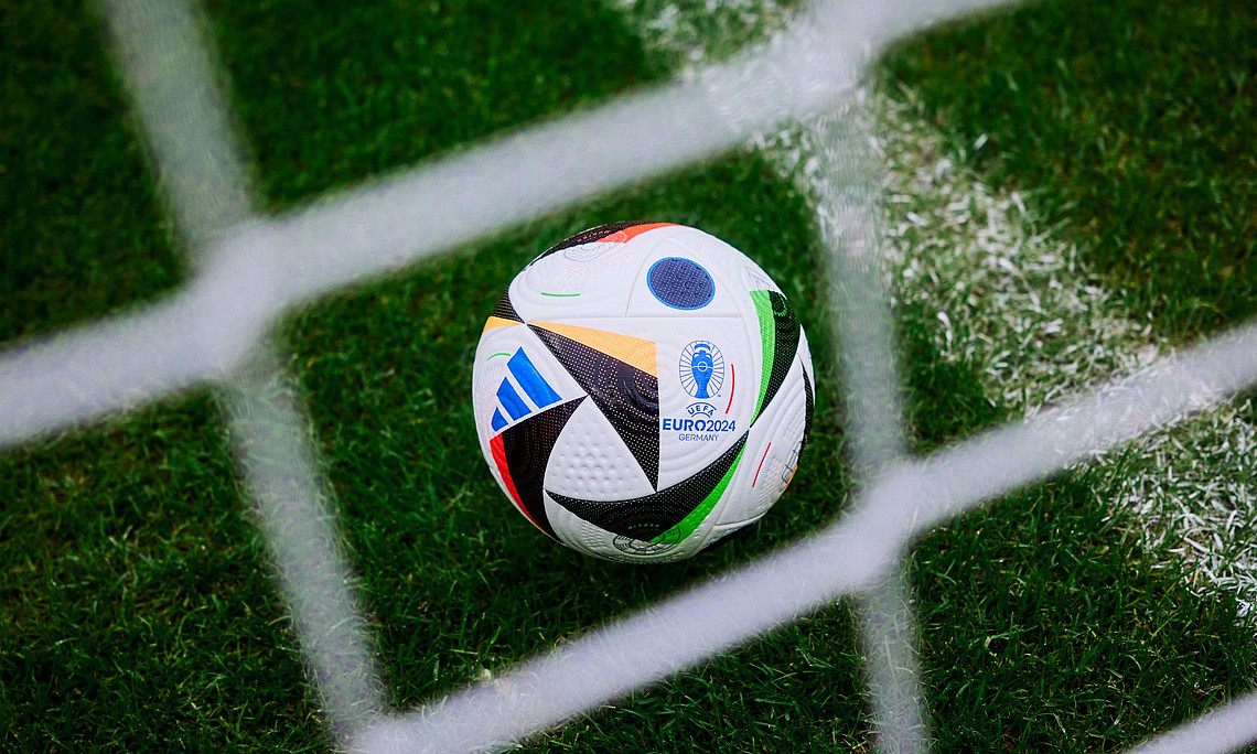 Ein Fußball hinter einem Tornetz auf einem Fußballfeld