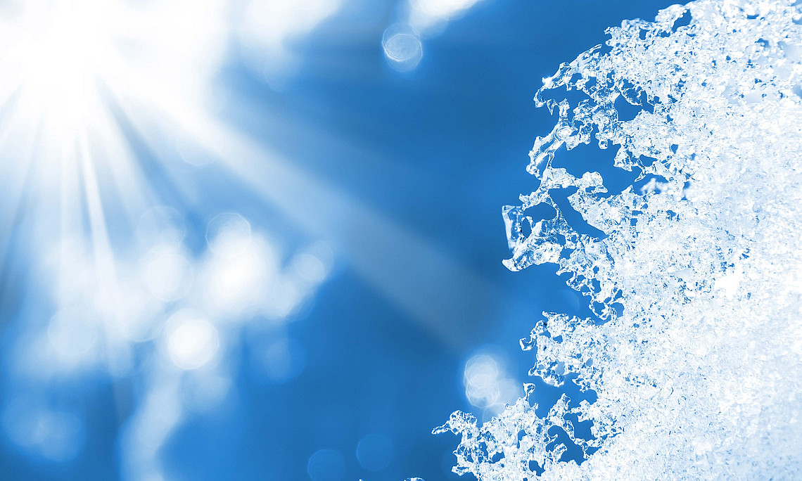 Die Sonne scheint von blauem Himmel auf schmelzenden Schnee