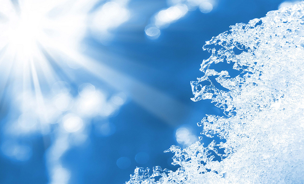 Die Sonne scheint von blauem Himmel auf schmelzenden Schnee