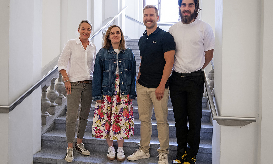 Eva Roblegg, Atida Selmani, Lukas Vergeiner und James MacFarlane Hoad stehen nebeneinander im Stiegenhaus am Institut für Pharmazeutische Wissenschaften