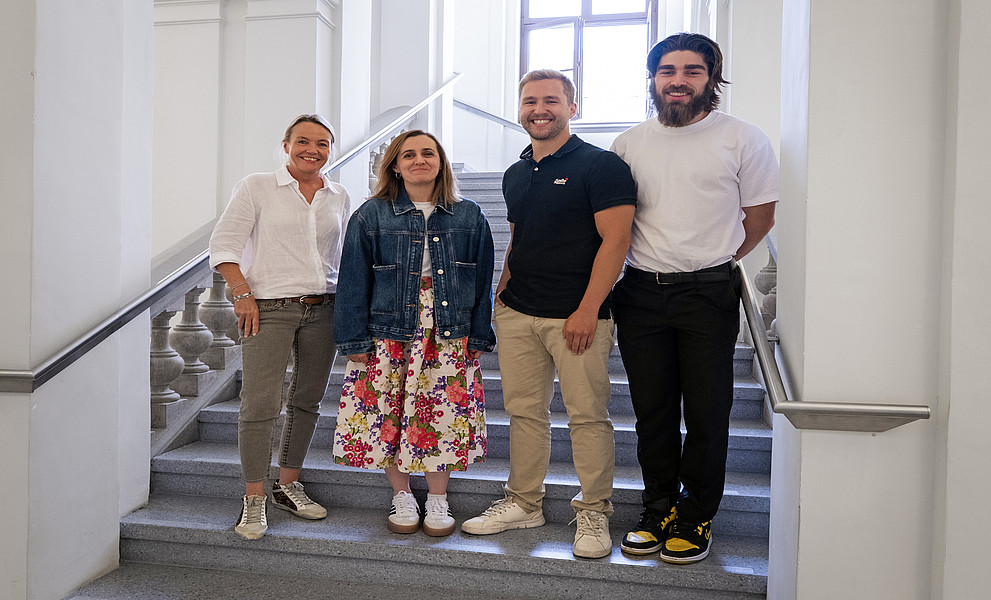 Eva Roblegg, Atida Selmani, Lukas Vergeiner und James MacFarlane Hoad stehen nebeneinander im Stiegenhaus am Institut für Pharmazeutische Wissenschaften