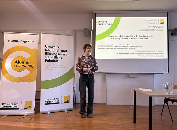 eine Frau, die vor zwei Rollups und einer Leinwand steht und einen Vortrag hält ©Uni Graz/Schmieder