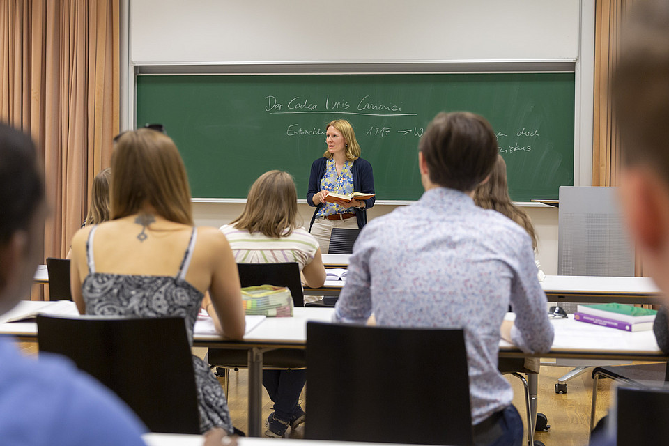 Eine Lehrende unterrichtet Studierende in einem Seminarraum.