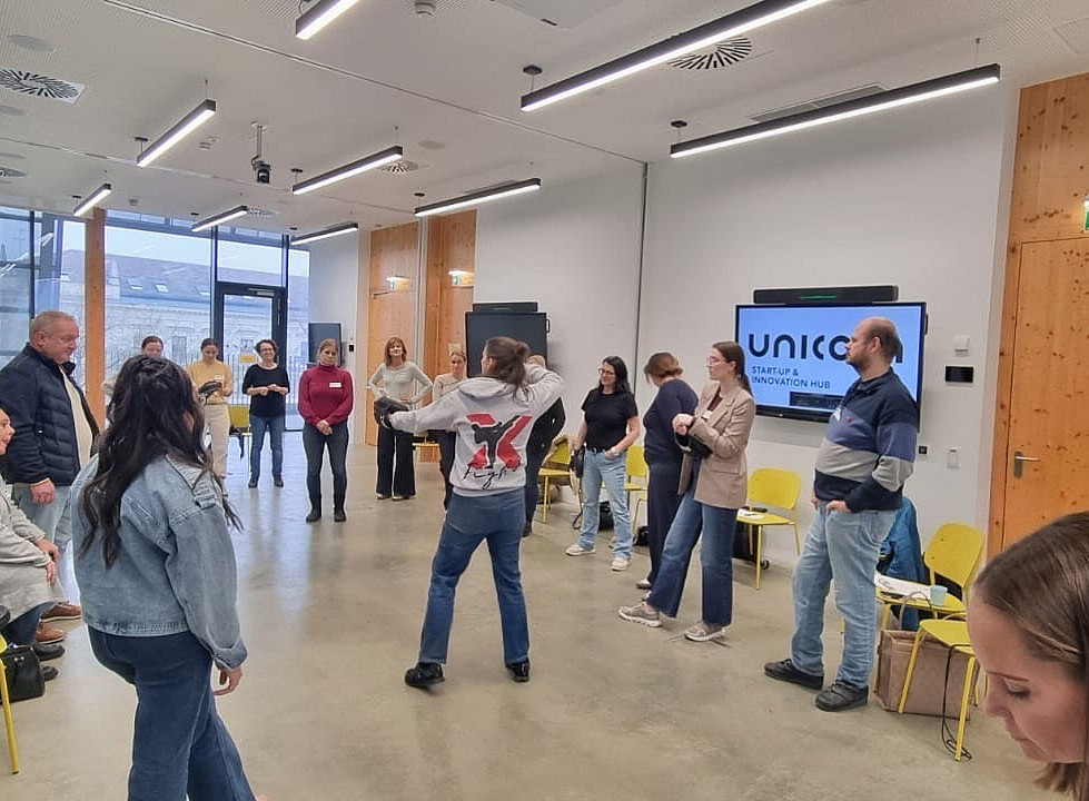 ein Stuhlkreis mit einer Mitte, wo Menschen Abwehrtechniken trainieren 