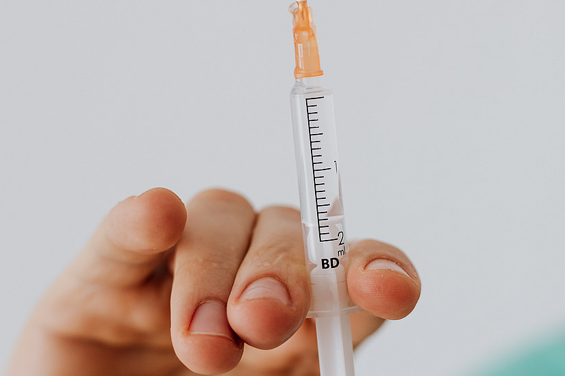 Spritze und Arzt bei Coronaimpfung