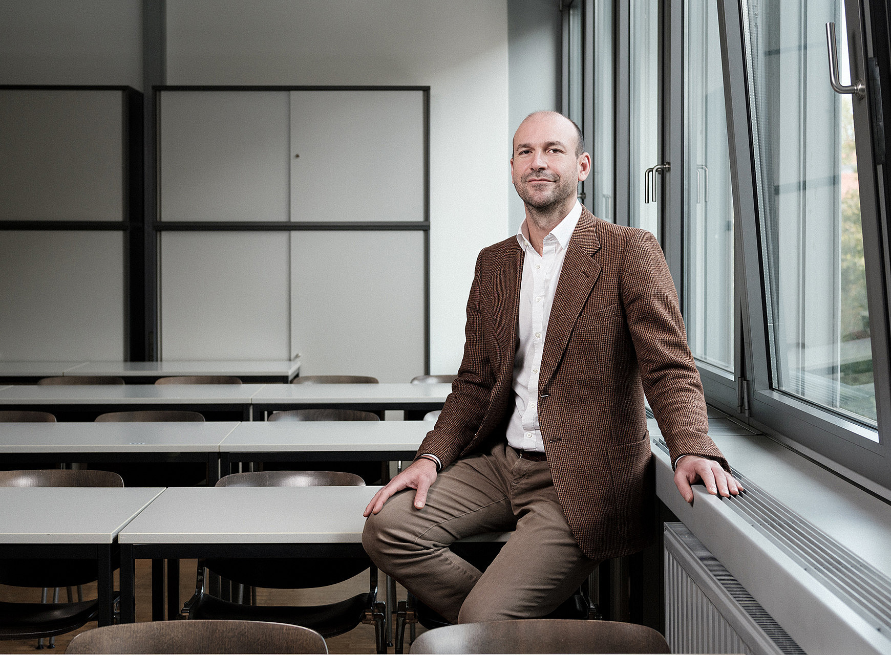 Friedensforscher Maximilian Lakitsch sitzt in einem Hörsaal. 