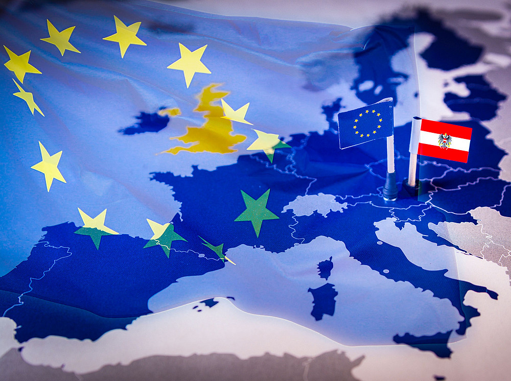 EU-Fahne vor einer Europakarte mit einem EU- und Österreichfähnchen symbolisiert den Arbeitsbereich Geschichte Österreichs und Zentraleuropas. ©tanaonte - stock.adobe.com