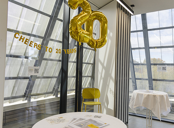 Goldene Luftballons in Form der Zahl 20 hängen in einem Veranstaltungsraum. Daneben steht „CHEERS TO 20 YEARS“. ©@foto-gasser.at