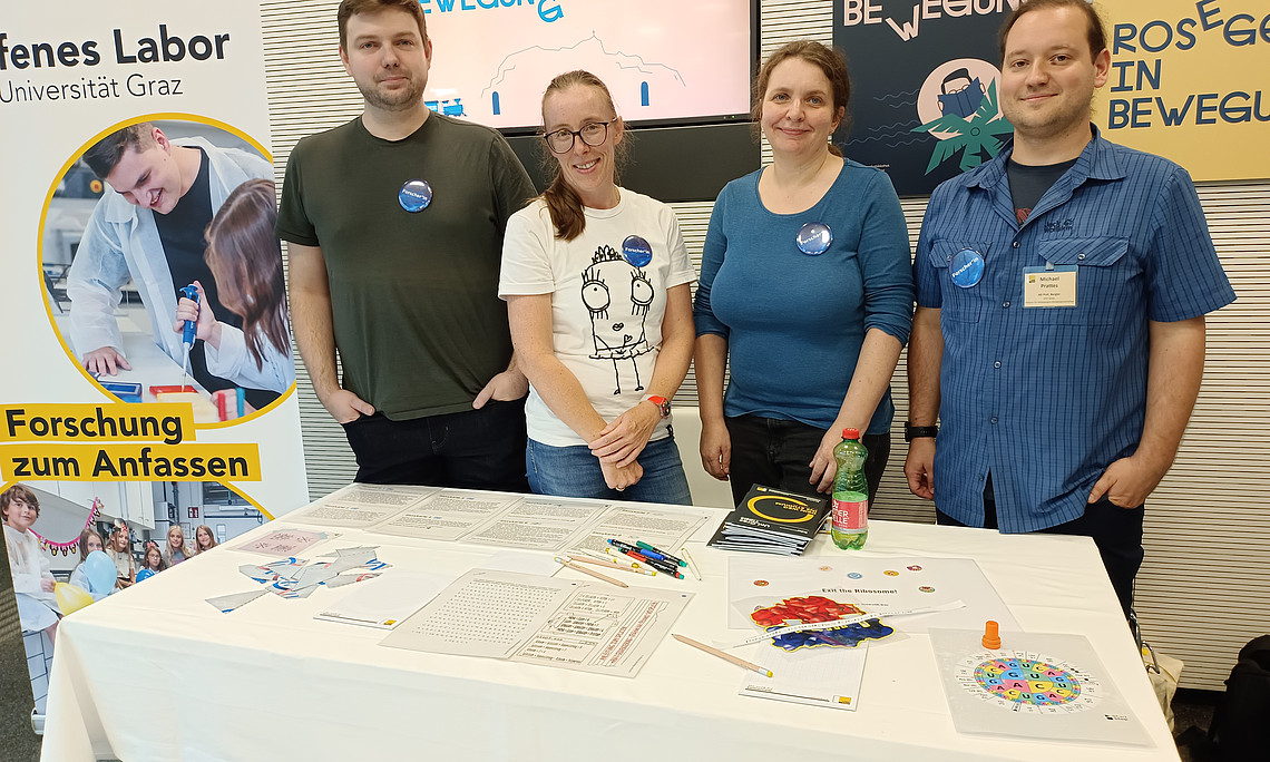 Forschende der Uni Graz auf der European Researchers Night stehen hinter einem Tisch auf dem sie ihr Projekt ausgestellt haben