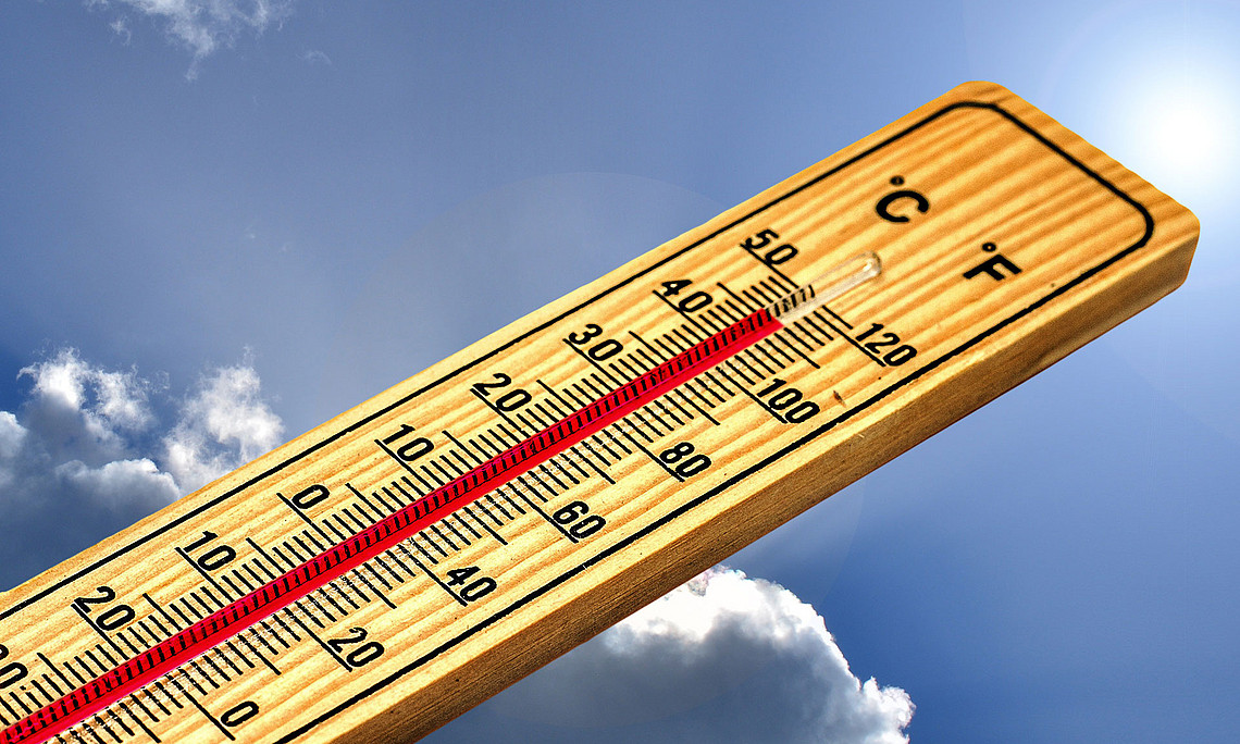 Thermometer, das 46 Grad Celsius anzeigt, vor blauem Himmel mit Wolken