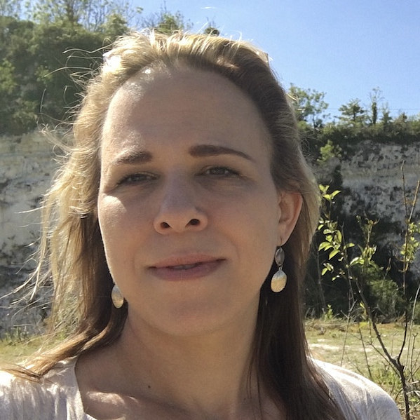 Das Foto zeigt Yvonne Živković, eine Frau mit langen Haaren, die Ohrringe trägt und im Freien für ein Selfie posiert. Im Hintergrund ist eine felsige Klippe unter einem klaren blauen Himmel zu sehen, mit grünen Bäumen und Sträuchern. ©Yvonne Živković