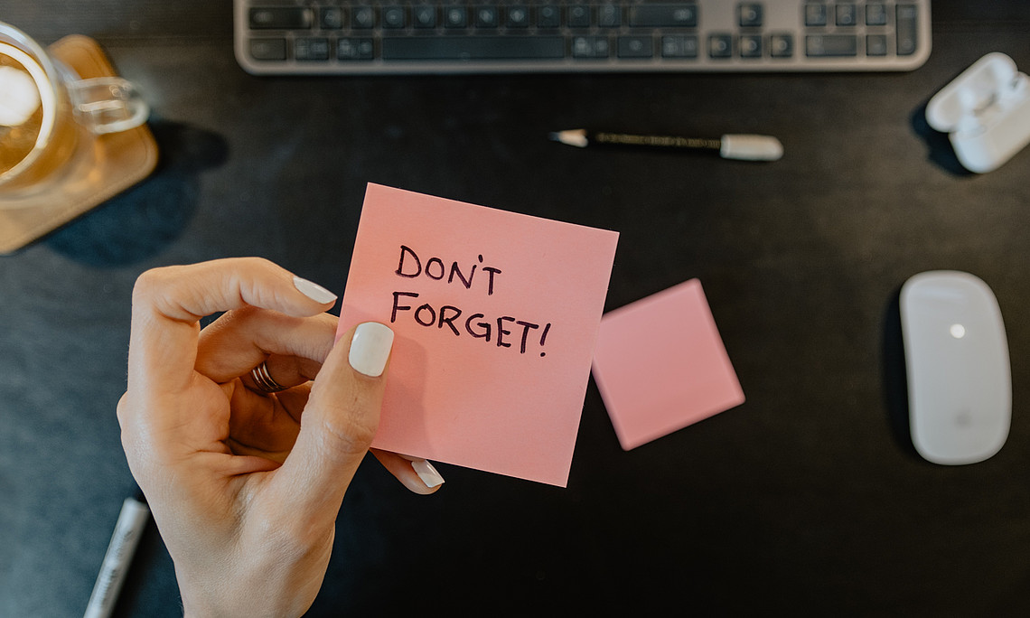 Eine Person, die eine Notiz hält, auf der steht: Don't forget