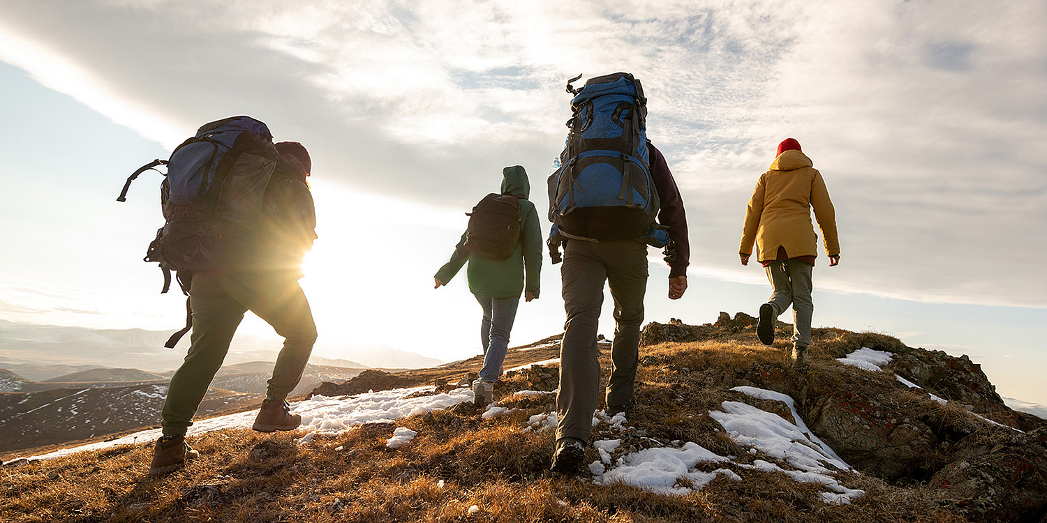 Gruppe von Wandernden, die der Sonne entgegen gehen.