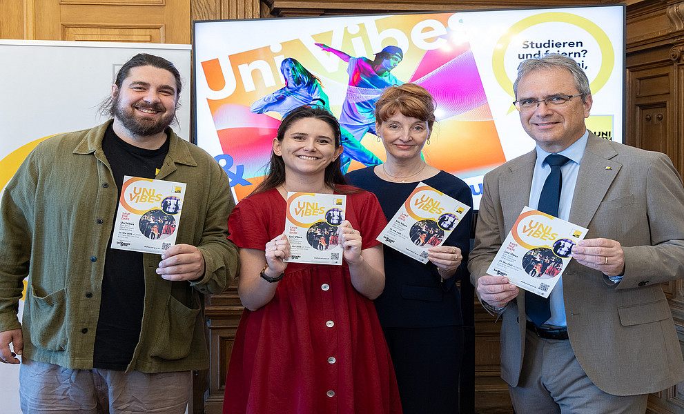 Vier Personen stehen nebeneinander und halten jeweils einen Flyer in der Hand.