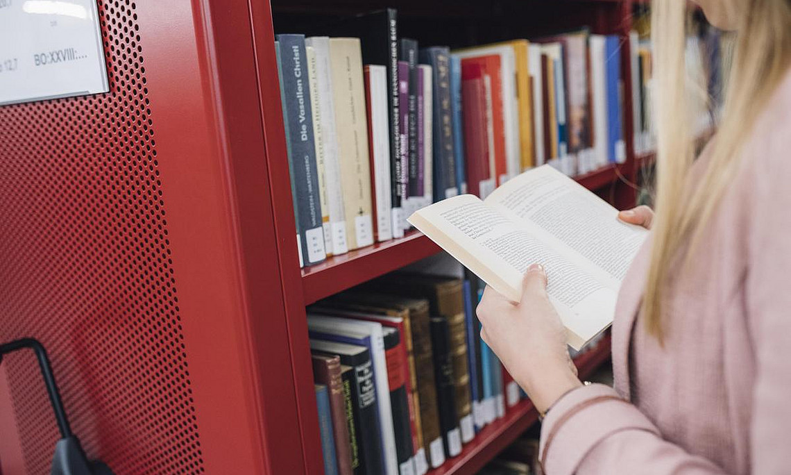 Eine Studierende der Uni Graz, die ein Buch in der Hand hält und liest.