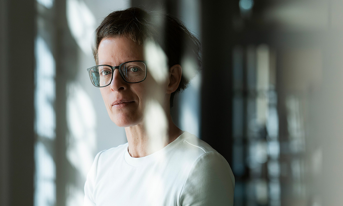 Portrait of Heike Karge photographed through a pane of glass