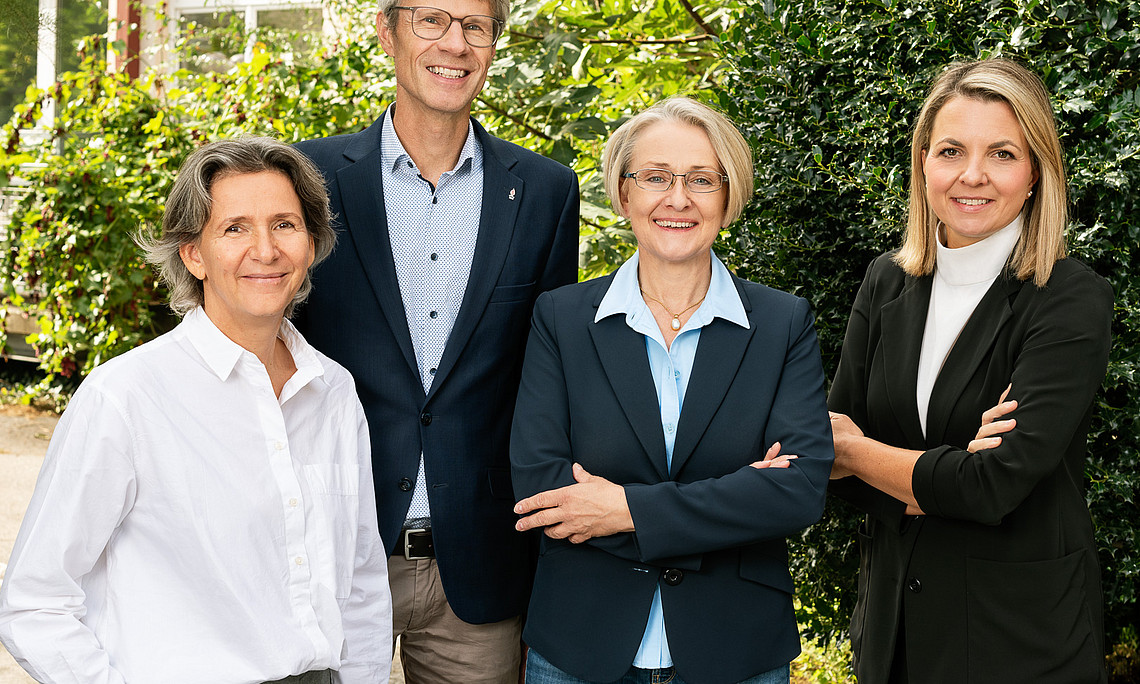 Team der Fakultätsleitung vor grünem Hintergrund