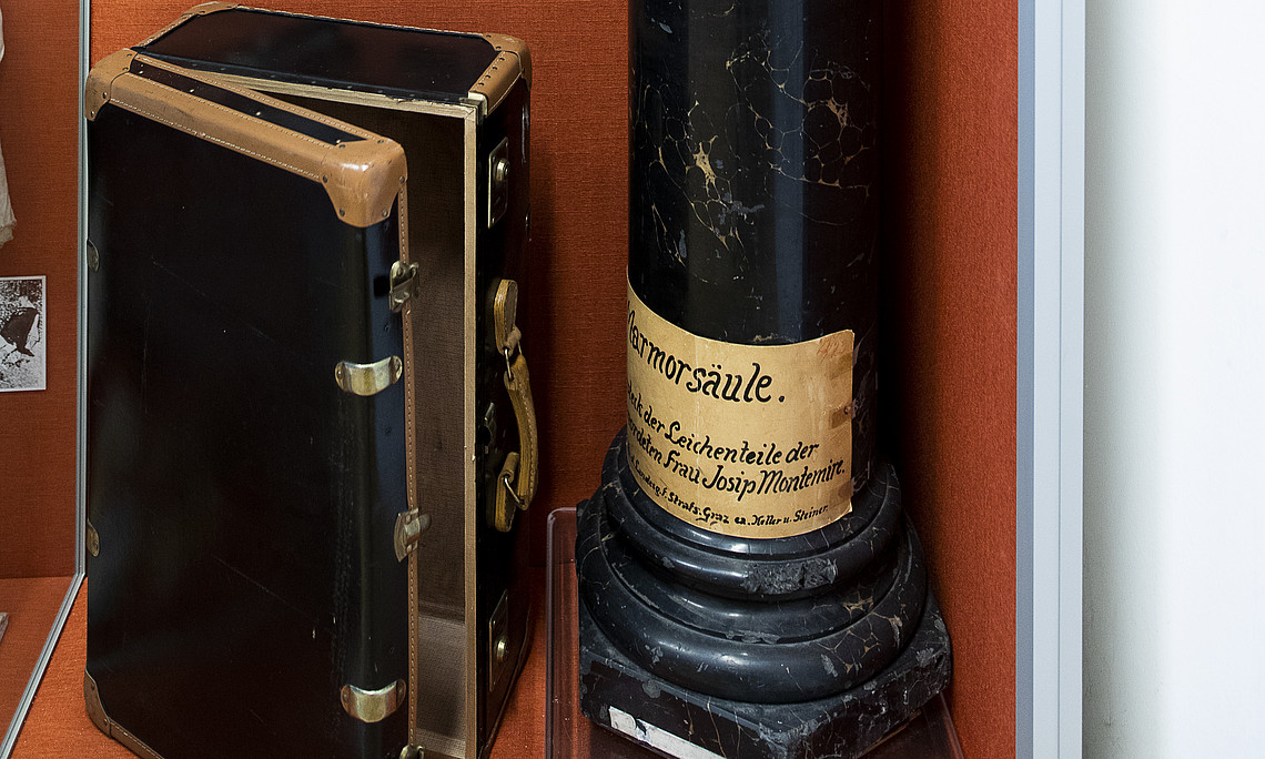 Vitrinenansicht der Ausstellung im Hans Gross Kriminalmuseum mit hölzerner Säule