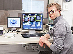 Person sits at a desk and looks into the camera ©BioTechMed-Graz