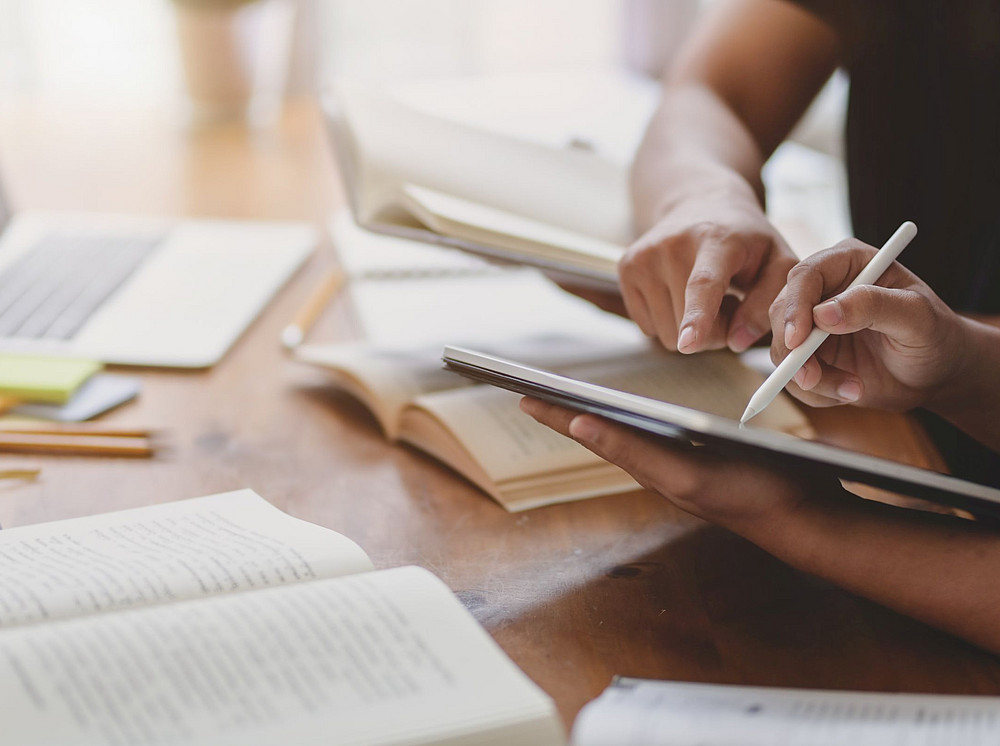 Zwei Personen sitzen an einem Schreibtisch vor einem aufgeklappten Laptop und aufgeschlagenen Büchern und symbolisieren das Projekt EQui-T am Forschungszentrum Inklusive Bildung. ©bongkarn - stock.adobe.com