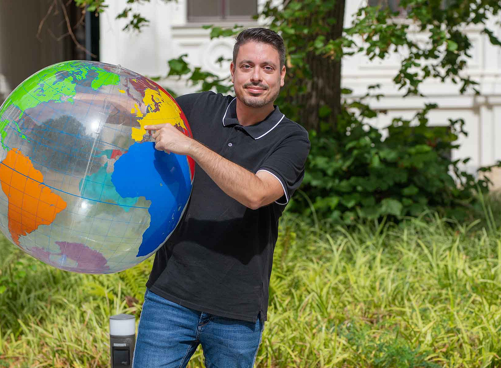 A man is holding a large ball shaped like a globe in his hand ©Uni Graz/Weber