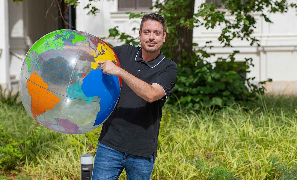 ein Mann hält einen großen Ball in Form einer Weltkugel in der Hand