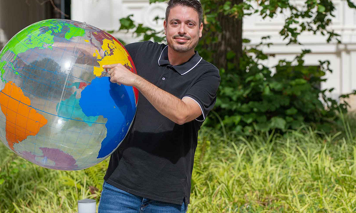 A man is holding a large ball shaped like a globe in his hand