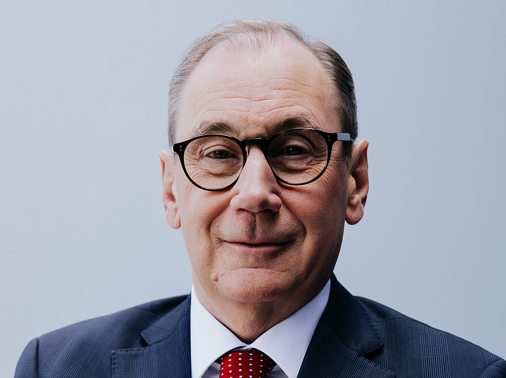 Martin Schallerl, Generaldirektor der Raiffeisen-Landesbank Steiermark in einem blauen Anzug mit einer roten Krawatte auf grauem Hintergrund ©RLB / Lupi Spuma